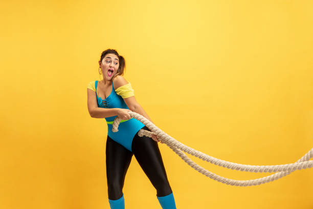 istock Young caucasian plus size female model's training on yellow background 1189923165