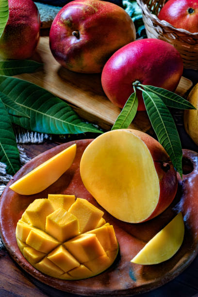 istock Tropical Fruits: Sliced mangos in a clay rustic plate on a wooden table in rustic kitchen 1189924287
