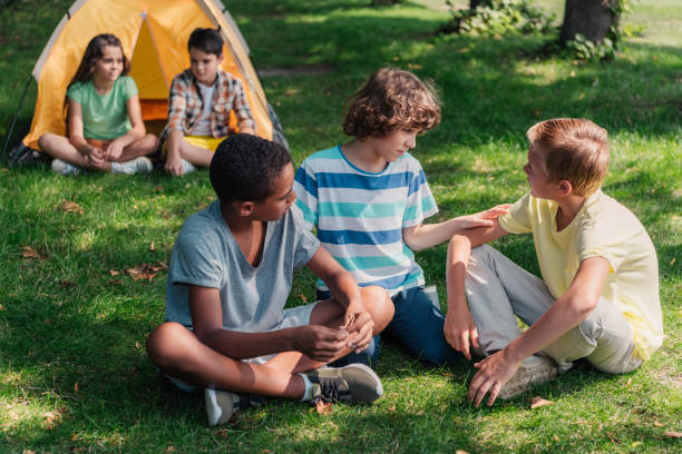istock selective focus of multicultural boys sitting on grass 1189925627