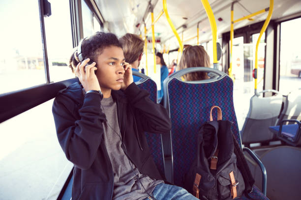 ragazzo che ascolta musica mentre viaggia in autobus - transportation bus mode of transport public transportation foto e immagini stock
