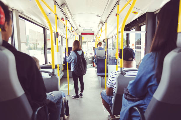 Males and females commuting by public transport Men and women traveling in public transport. Teenage girl is standing at aisle while commuting by bus. They are in vehicle. commercial land vehicle stock pictures, royalty-free photos & images