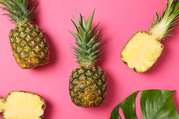 istock Pineapples and palm leaf on pink background, top view. Juicy fruit 1189927192