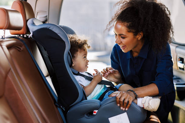 Happy mother looking at her son in a baby seat. Young female preparing kid for a trip. Happy mother looking at her son in a baby seat. Young female preparing kid for a trip. back seat photos stock pictures, royalty-free photos & images