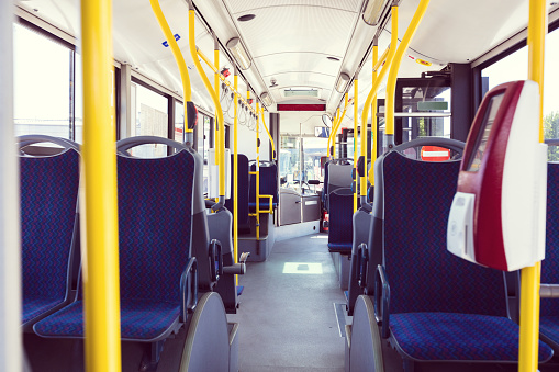 Contactless machine in bus. Empty blue seats in public transport. Interior of vehicle.