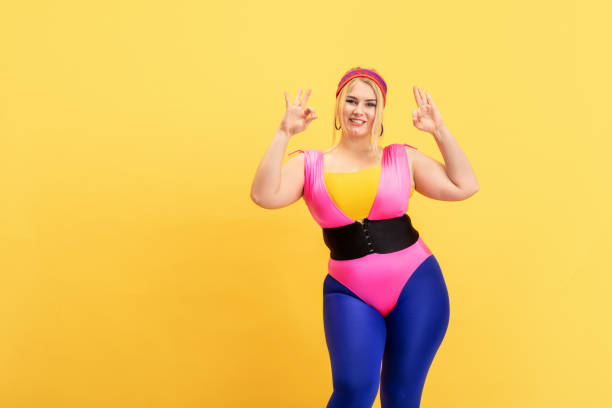 istock Young caucasian plus size female model's training on yellow background 1189932873
