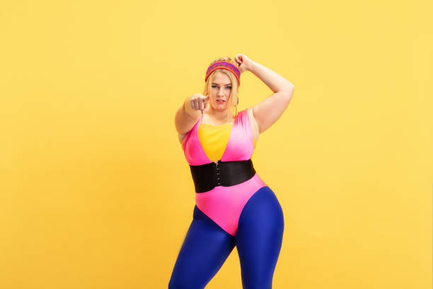 istock Young caucasian plus size female model's training on yellow background 1189932888