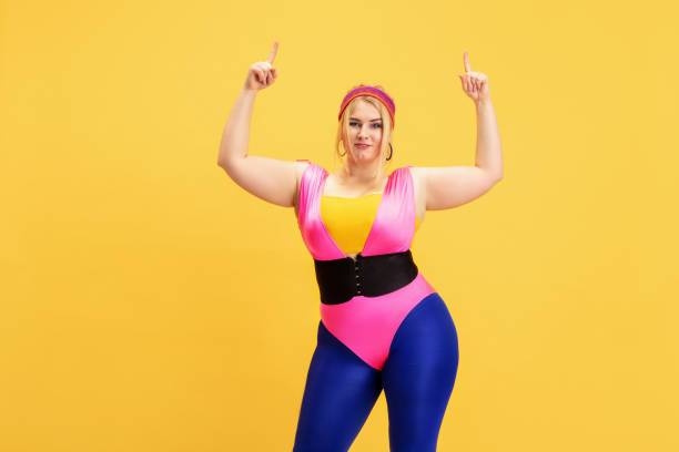 istock Young caucasian plus size female model's training on yellow background 1189932898