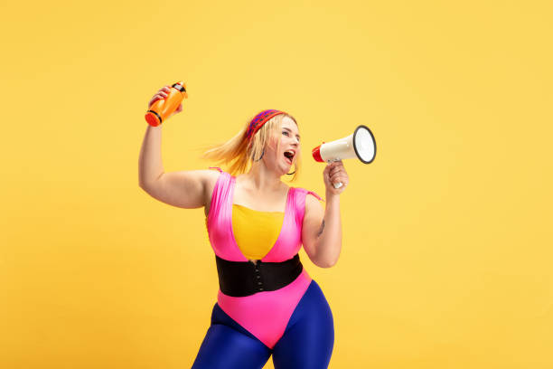 istock Young caucasian plus size female model's training on yellow background 1189933050