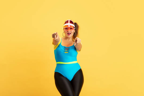 istock Young caucasian plus size female model's training on yellow background 1189933514