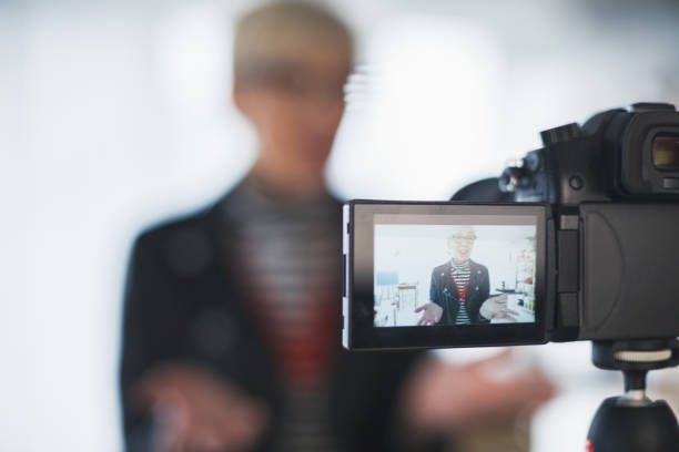 Image of mature female vlogger on camera flip screen