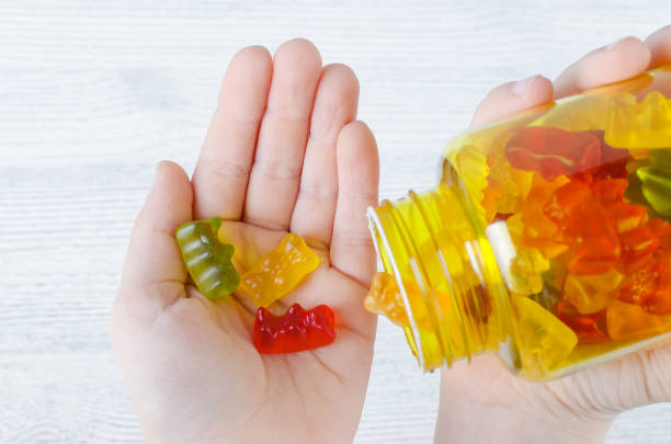 ребенок держит витамины для детей, как желе конфеты - capsule vitamin pill red orange стоковые фото и изображения