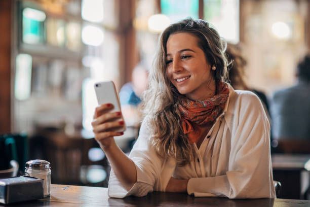istock Beautiful woman using phone in cafe 1189934240