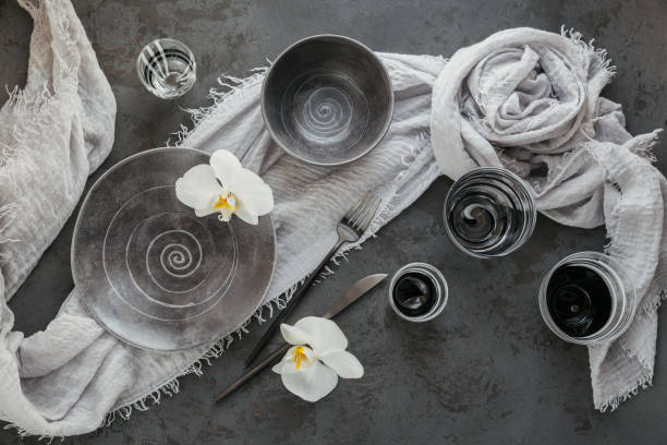 istock Elegance table setting with knitted grey napkin, cutlery, ceramic plates, glasses and white orchid flowers 1189935126