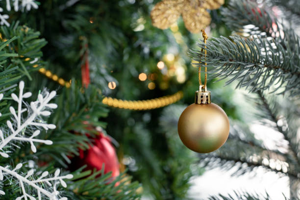 istock Gold ball hanging from a decorated Christmas tree. 1189935252