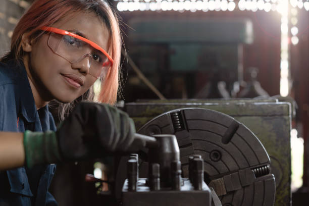 ingegnere femminile dell'asia etnica che opera macchinari industriali pesanti in fabbrica di produzione - operaio di produzione foto e immagini stock