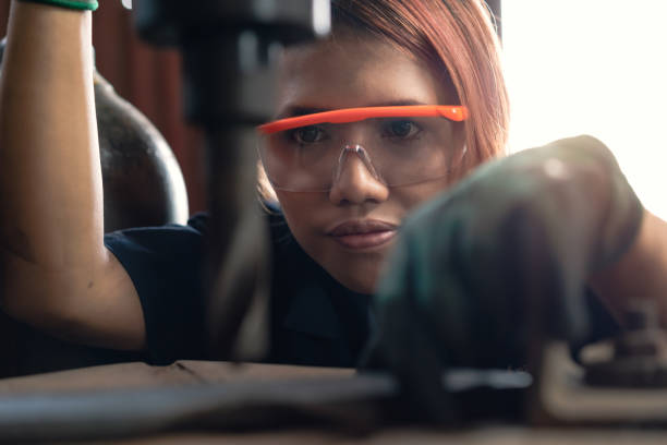 mulher diversa nova que concentra-se ao operar a máquina industrial da perfuração - auto repair shop mechanic garage workshop - fotografias e filmes do acervo