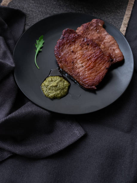istock fried meat steaks with pesto on a black dish. 1189936802