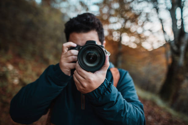 young man using a dslr camera in a forest in autumn - nature photographer imagens e fotografias de stock