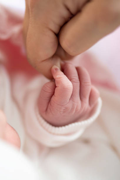 Family, childhood and parenthood concept. Little newborn baby sleeping on mother chest, dad brushing child hair . Red background