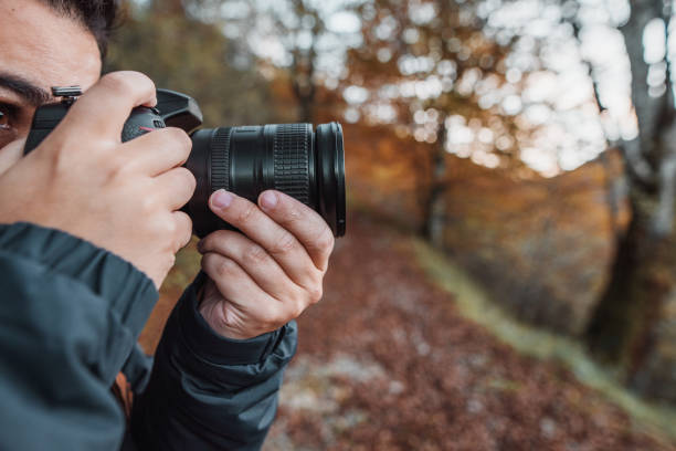 istock Young man using a DSLR camera in a forest in autumn 1189946168