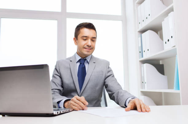 istock smiling businessman with laptop and papers 1189948023