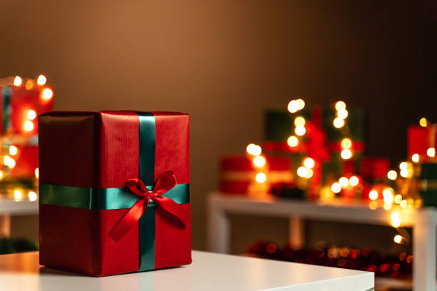 istock Christmas present on white table in front defocused Christmas lights in background, bokeh 1189949924