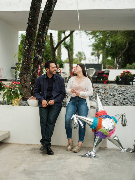 padre latino e daughte in piedi fuori casa accanto a pi-ata - pinata mexico christmas mexican culture foto e immagini stock