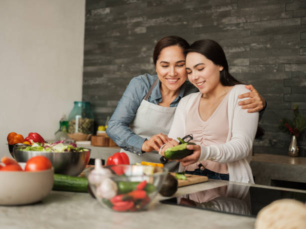 Loving latin mother teaching daughter to cook at home A loving latin mother teaching her teenage daughter how to cook. family dinners and cooking stock pictures, royalty-free photos & images