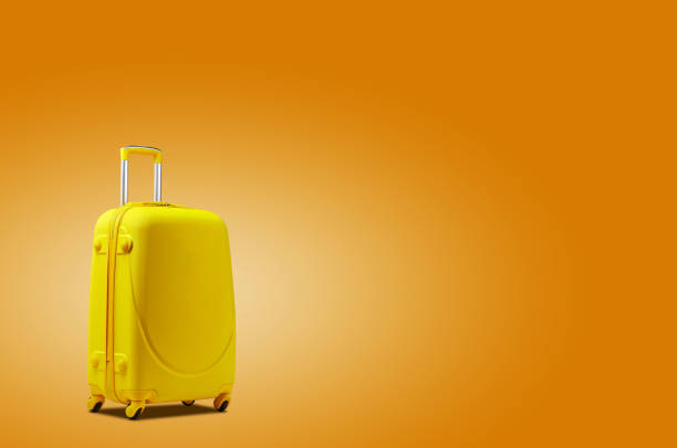 istock Yellow suitcase is standing against an orange background. A realistic shadow is drawn in under it. Collage. Copy space, close-up 1189957208