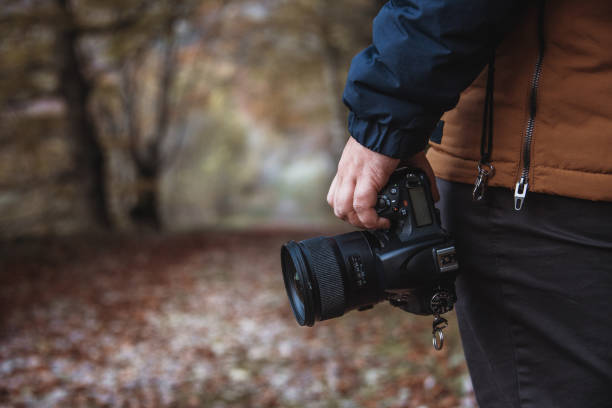 istock Hand holding a DSLR camera in a forest in autumn 1189957992
