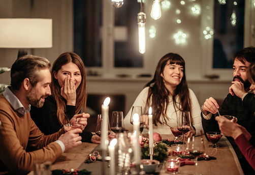 Male and female friends enjoying Christmas dinner party at home