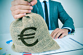 junger-mann-im-anzug-mit-einer-sackleinen-geldtasche-mit-dem-euro-zeichen.jpg?b=1&s=170x170&k=20&c=8w55S6diJFkxQ-3sGAdp4n65jUXOS0sMd7BLoLf0k0k=