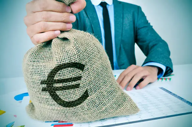 Photo of young man in suit with a burlap money bag with the euro sign