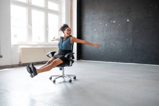 imprenditrice africana che si prende una pausa in ufficio e rotola sulla sedia dell'ufficio - friday foto e immagini stock