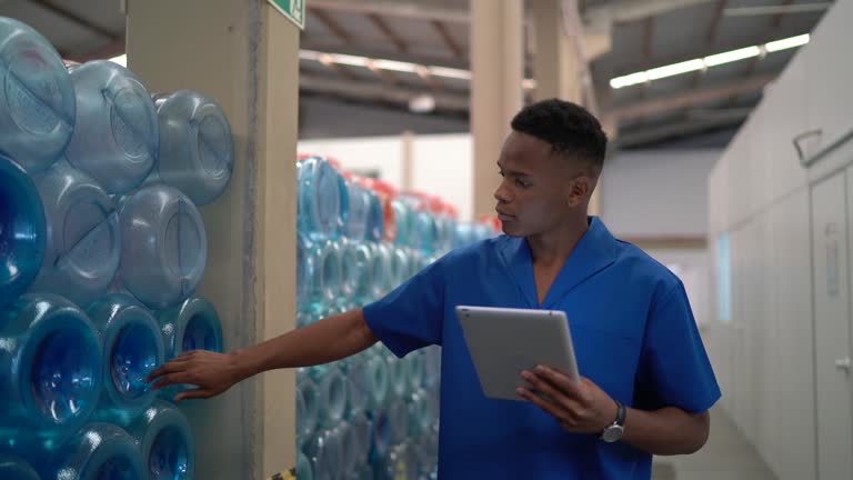 Young employee walking and using digital tablet in industry