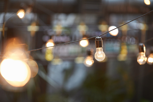 Background image of outdoor lighting garlands , focus on classic light bulb with wiring, copy space
