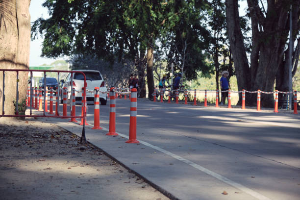 palo di regolazione del traffico e striscia di rombo su strada asfaltata nel parco pubblico con le persone che esercitano lo sfondo la sera della giornata di sole. il simbolo della sicurezza prima di tutto. - rumble strip foto e immagini stock