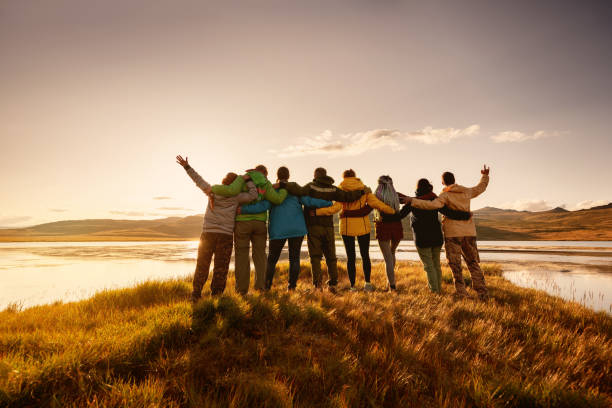 Happy big family hugging together in mountains Big happy family is standing and hugging together against lake in mountains and sunset sky group mountain silhouette stock pictures, royalty-free photos & images