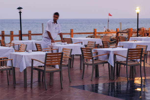 ALANYA, TURKEY, 29th JULY, 2009: A waiter is preparing tables for dinner in A la Carte restaurant on the Mediterranean sea.