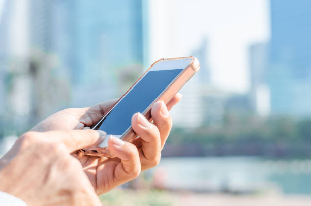 istock close up business man using hand typing smartphones and touch screen working search with app devices outdoor in city with sunrise and building background. 5G technology connecting the world. 1189971814
