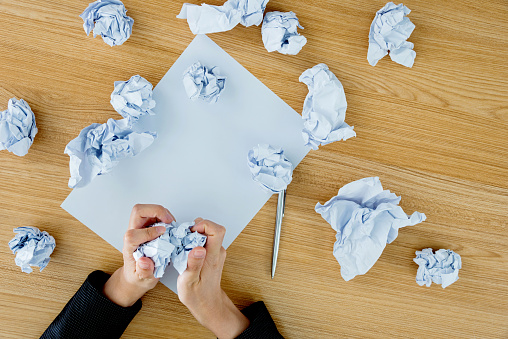 Businesswoman rubbing crumpled paper in office.