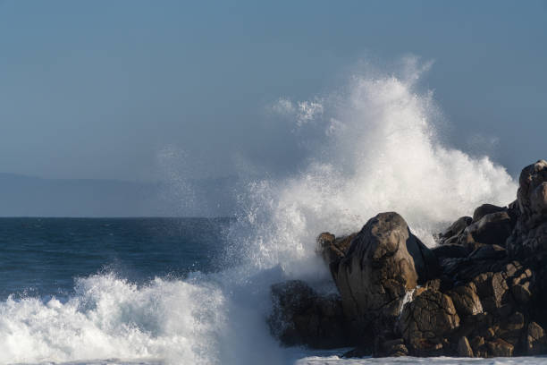 istock Wave crashing onto jagged rocks 1189973724