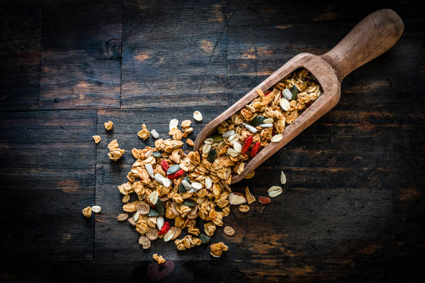 Healthy eating: Wooden serving scoop filled with granola shot from above on dark wooden table.High resolution 42Mp studio digital capture taken with Sony A7rii and Sony FE 90mm f2.8 macro G OSS lens