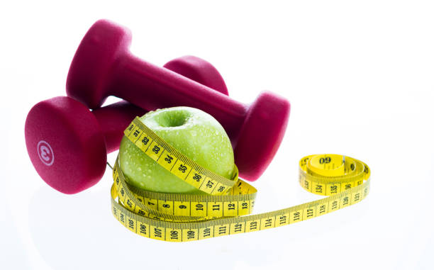 istock Green apple with a measuring tape and dumbbells 1189975295