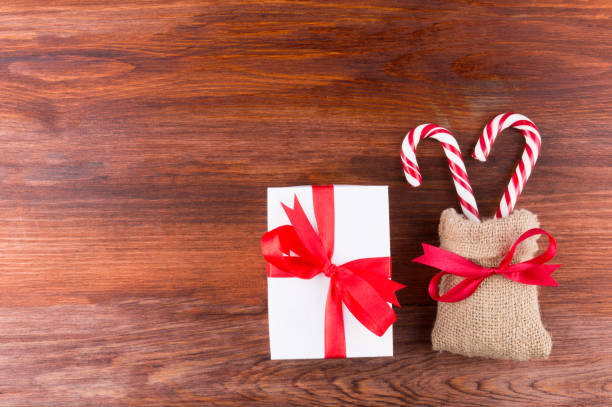istock two candy canes with white gift box red ribbinon bow on dark wooden board 1189975384