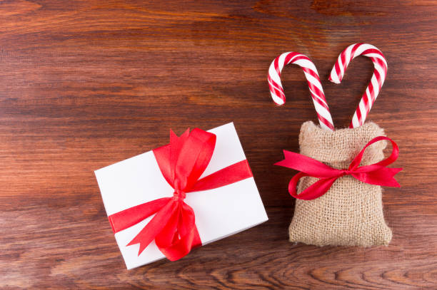 istock two candy canes with white gift box red ribbinon bow on dark wooden board 1189975398