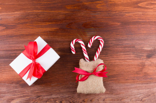 istock two candy canes with white gift box red ribbinon bow on dark wooden board 1189975404
