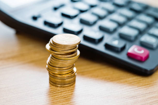 Calculator and coins on wooden table.