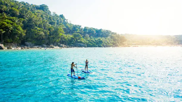 Shot of a man and woman paddle boarding across the sea