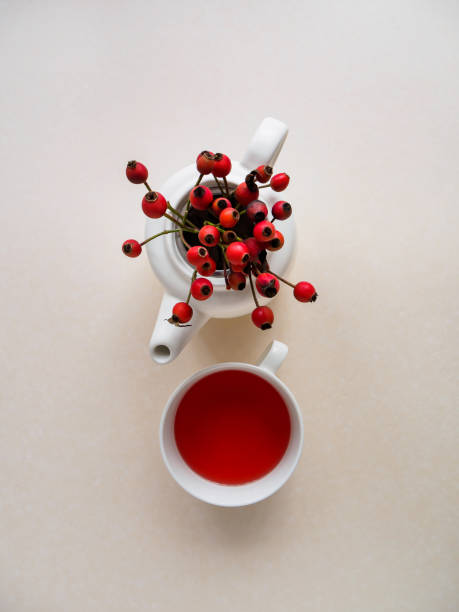istock Teapot with fresh rosehips and a cup on a white table 1189978313